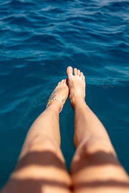Yaz havası. Suda dinlenen, bronzlaşan, bacaklarını suya sıçratan bir kadının güzel ince bacakları. Dinlenen bir kız..