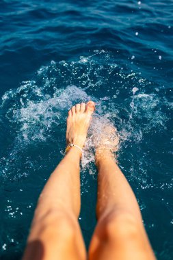 Yaz havası. Suda dinlenen, bronzlaşan, bacaklarını suya sıçratan bir kadının güzel ince bacakları. Dinlenen bir kız..