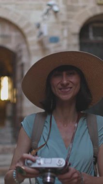 Dikey çekim. Kameralı kadın fotoğrafçı dışarıda fotoğraf çekiyor. Dışarıdaki kameralı kız. Şehir turu ve yürüyüş. Yaşam tarzı, seyahat ve insan konsepti.