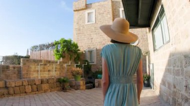 Kız tatilden ve şehirde gezmekten zevk alıyor. Eski Jaffa şehrinde güzel caddelerde yürüyen elbiseli genç bir kadın. İsrail. seyahat ve macera.