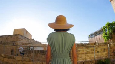 Elbiseli ve şapkalı kız. Eski Jaffa şehrinde güzel caddelerde yürüyen elbiseli genç bir kadın. İsrail. seyahat ve macera.