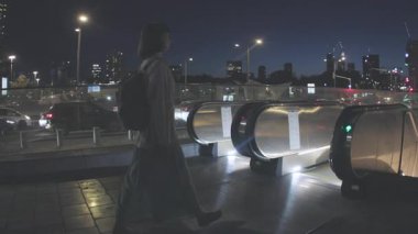 Metro istasyonunda yürüyen merdivenden inen bir kız şehir seyahatini ve modern ulaşımı gösteriyor. Metroda yürüyen merdivenden inen bir turist.