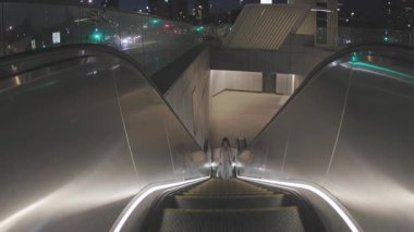 Kız metro istasyonunda yürüyen merdivene çıkıyor. Şehir içi ulaşımı ve modern ulaşımı gösteriyor. İsrail metrosu. Tel Aviv 'de. İsrail.