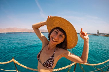 Yaz havası. Bikinili genç, sıska bir kadın denizin kenarında duruyor ve kameraya gülümsüyor. Kız yaz tatilinin tadını çıkarıyor. Kızıl Deniz 'de tatil, Eilat. İsrail.