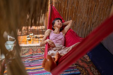 Hamakta yatan kız. Yaz tatilinin tadını çıkaran mutlu genç bir kadın. Romantik tasasız ruh hali konsepti. Yaz havası.