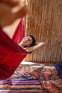 Tatilde hamakta dinlenen sakin bir genç kadın. Kız rahat bir şekilde dışarıda hamakta sallanıyor, stressiz bir hayat sürüyor. Yaz havası.