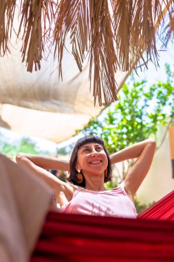 Tatilde hamakta dinlenen sakin bir genç kadın. Kız rahat bir şekilde dışarıda hamakta sallanıyor, stressiz bir hayat sürüyor. Yaz havası.