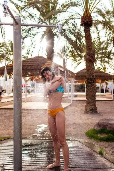 Yaz havası. Güneşli bir günde, plajdaki lüks bir otelde mayo giymiş esmer, beyaz bir kadın ferahlatıcı bir tropikal duş alıyor. Mayolu kız..