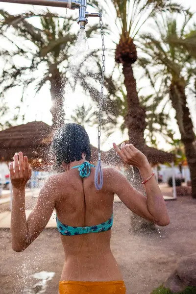 Yaz havası. Güneşli bir günde, plajdaki lüks bir otelde mayo giymiş esmer, beyaz bir kadın ferahlatıcı bir tropikal duş alıyor. Mayolu kız..