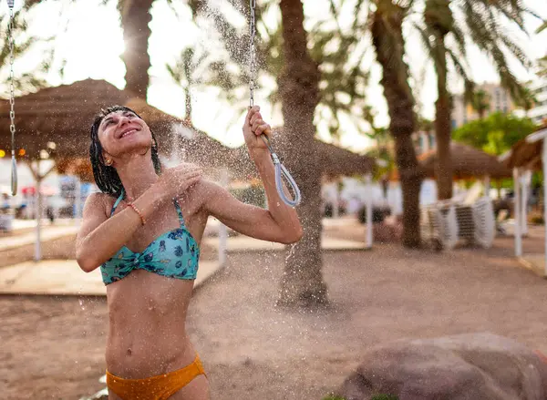 Yaz havası. Güneşli bir günde, plajdaki lüks bir otelde mayo giymiş esmer, beyaz bir kadın ferahlatıcı bir tropikal duş alıyor. Mayolu kız..