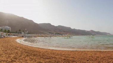 Sahilden güzel bir Ölü Deniz tatil köyüne. Otelin yanındaki plajda güneş pansiyonları ve şemsiyeler. İsrail 'de tatil