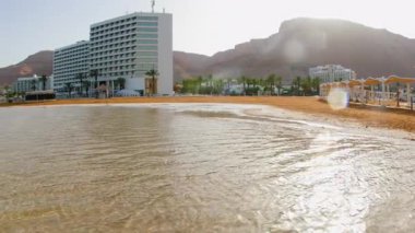Sahilden güzel bir Ölü Deniz tatil köyüne. Otelin yanındaki plajda güneş pansiyonları ve şemsiyeler. İsrail 'de tatil
