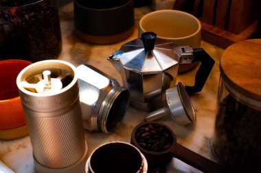 Moka kahve makinesi. Kahve yapmak için gerekli malzemeler. Moka ve kahve çekirdekleri sıcak bir mutfağın masasında. Evde kahve yapıyorum. Kahve kültürü.