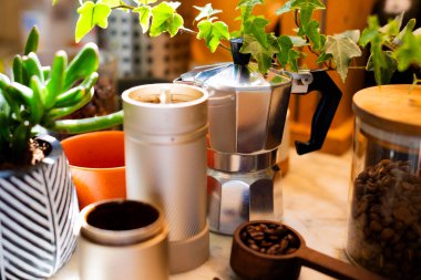 Kahve yapmak için gerekli malzemeler. Kahve makinası, kahve değirmeni ve kahve çekirdekleri rahat bir mutfağın masasında. Kahve yapmak..