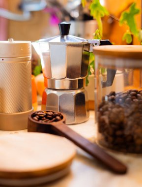 Kahve yapmak için gerekli malzemeler. Kahve makinası, kahve değirmeni ve kahve çekirdekleri rahat bir mutfağın masasında. Kahve yapmak..