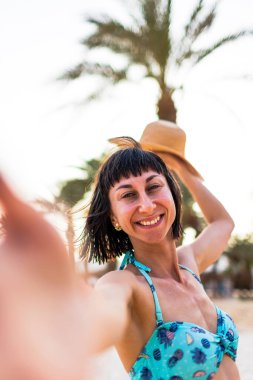Elinde şapkası olan güzel bir genç kadının portresi. Yaz havası. Kameraya gülümseyen ve tatilin tadını çıkaran mutlu kadın. Mayolu kız..
