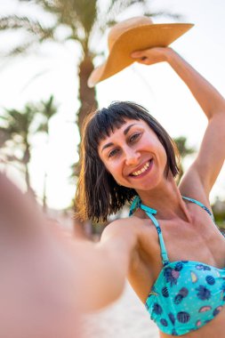 Yaz havası. Kadın erkeğinin tatilde ya da balayında okyanus kıyısında kendisine eşlik etmesini istiyor. Mutlu bronzlaşmış kadın portresi.