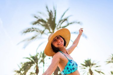Şapkalı güzel bir genç kadının portresi. Yaz havası. Kameraya gülümseyen ve sahilde tatilin tadını çıkaran mutlu kadın. Mayolu kız..