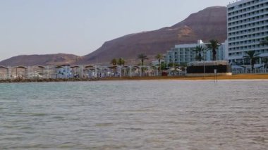 Ölü Deniz. Dağlar ve su manzarası. Otel ve deniz kıyısında bir sahil. İsrail 'de tatil. Ölü Deniz. İsrail