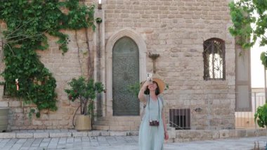 Telefon kullanan şık bir kız. şehir tarzı ve moda. Elinde telefonla şehirde dolaşan bir turist. Maceralar ve yolculuklar.