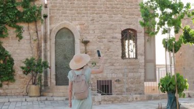 Kameralı mutlu kız şehirde dolaşıyor. Genç turist şehri geziyor ve geziyor. Etrafta dolaşan bir turist