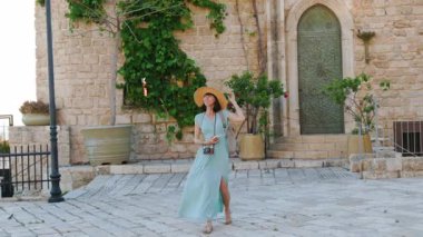 Açık havada yürüyorum. Neşeli gülümseyen stil sahibi kadın turist. Eski şehrin sokaklarında yürüyen bir gezgin. Seyahat ve tatil.