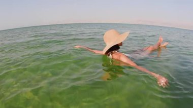 Ölü Deniz 'de yüzmekten zevk alan bir kız. Talassotherapy gören bir kadın, Ölü' nün açık yeşil sularında sakin bir şekilde yüzüyor.