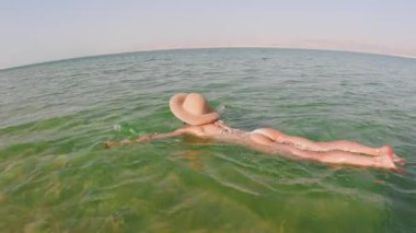 Ölü Deniz 'de yüzmekten zevk alan bir kız. Talassotherapy gören bir kadın, Ölü' nün açık yeşil sularında sakin bir şekilde yüzüyor.