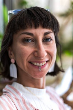 Mutlu kadın portresi ve alt dudağında piercing, kendine güven veya şehirde neşeli bir tutum. Kadın, esmer, gülümseyen kamera, mücevher ve şık moda şehirlerde.