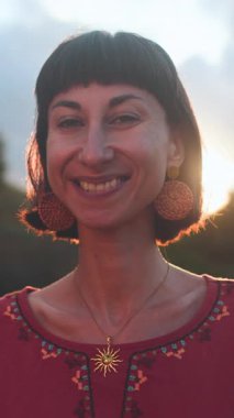 Dikey çekim. Romantik bir ruh hali. Gün batımında güzel bir elbise giymiş güzel bir kadının portresi. Kız gülümser ve bakar.