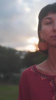 Dikey çekim. Romantik bir ruh hali. Gün batımında güzel bir elbise giymiş güzel bir kadının portresi. Kız gülümser ve bakar.