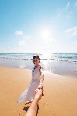 Beni takip edin. Mutlu genç bir kadın arkadaşının elini tutuyor. Birbirlerine aşık çiftler sahilde eğleniyorlar. Elbise giymiş güzel bir kız sahilde yürüyor, erkek arkadaşının elini tutuyor, romantik bir yürüyüş..