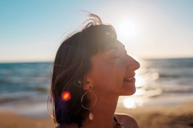 Yaz havası. Kumsalda güzel bir esmerin portresi. Genç mutlu kız gülümsüyor.