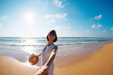 Beni takip edin. Mutlu genç bir kadın arkadaşının elini tutuyor. Birbirlerine aşık çiftler sahilde eğleniyorlar. Elbise giymiş güzel bir kız sahilde yürüyor, erkek arkadaşının elini tutuyor, romantik bir yürüyüş..