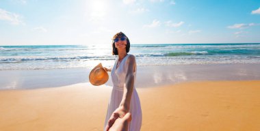 Mutlu genç bir kadın arkadaşının elini tutuyor. Birbirlerine aşık çiftler sahilde eğleniyorlar. Elbise giymiş güzel bir kız sahilde yürüyor, erkek arkadaşının elini tutuyor, romantik bir yürüyüş. Sevgililer Günü.