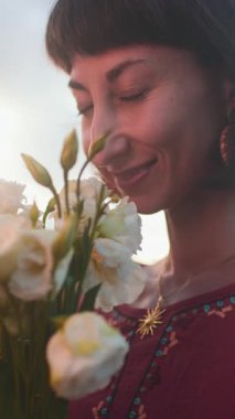 Dikey çekim. Romantik ruh hali. Gülümseyen kızlar buluşmada bir buket taze bahar çiçeği veriyorlar. Mutlu kızın yüzü çiçeklerden zevk alıyor..