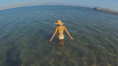 Kadın denize girer ve suyun üzerinde rahatça uzanır. Güzel Avrupalı kadın yaz tatillerinde denizde yüzer. Yaz havası.