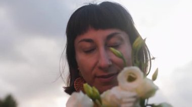 Gün ışığında bir buket taze bahar çiçeğiyle gülümseyen kadın yüzünü kapat. Çiçek tomurcuklarından hoşlanan mutlu kızın yüzü. romantik