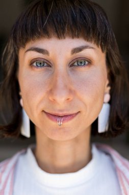 Mutlu kadın portresi ve alt dudağında piercing, kendine güven veya şehirde neşeli bir tutum. Kadın, esmer, gülümseyen kamera, mücevher ve şık moda şehirlerde.