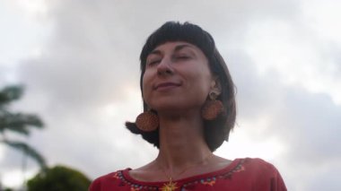 Kameraya bakan gülümseyen genç bir kadının portresi. Mutlu hissediyorum. Dışarıda, gün ışığında. Romantik bir ruh hali. Yavaş çekim