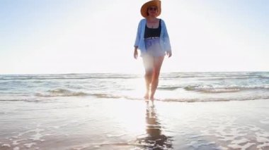 Kumsalda yürüyen mutlu ve boyunda bir kız. Vücut pozitif. Sahildeki kız. Yaz havası.