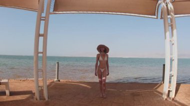 Ölü Deniz kıyısında tatilin tadını çıkaran bir kız. Thalassotherapy kadını, Ölü Deniz sahilinde sessiz bir yürüyüş yapıyor. İsrail. Güzel