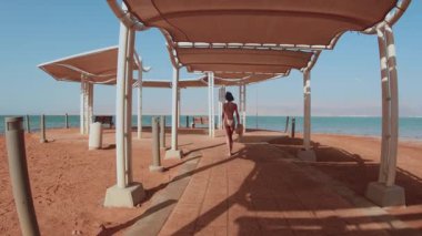 Ölü Deniz kıyısında tatilin tadını çıkaran bir kız. Thalassotherapy kadını, Ölü Deniz sahilinde sessiz bir yürüyüş yapıyor. İsrail. Güzel