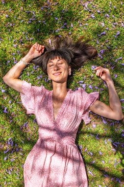 Yaz havası. Yeşil çimlerin ve çiçeklerin üzerinde yatan genç bir kadın. Yaz havası. Kız dışarıda vakit geçiriyor. Doğanın ve tatilin tadını çıkar. Mutlu kadın..