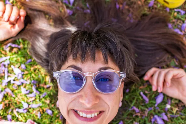 Yeşil çimenlerin ve çiçeklerin üzerinde yatan genç bir kadın. Şapka yüzünü örtüyor. Yaz havası. Kız dışarıda vakit geçiriyor. Doğanın tadını çıkar.