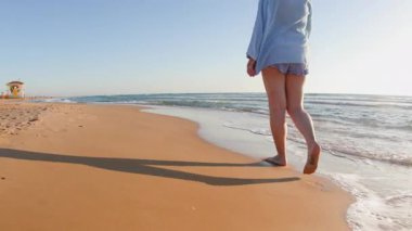 Kumsalda yürüyen mutlu ve boyunda bir kız. Vücut pozitif. Sahildeki kız. Yaz havası.