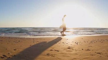Gün batımında kumlu sahilde yürüyen ve vücut pozitifliğinin tadını çıkaran mutlu artı beden kız. Sahildeki kız. Yaz havası.