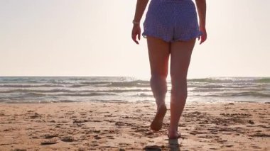 Gün batımında kumlu sahilde yürüyen ve vücut pozitifliğinin tadını çıkaran mutlu artı beden kız. Sahildeki kız. Yaz havası.