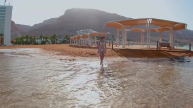 Yaz havası. Sıska kız İsrail 'de Ölü Deniz' in sahilinde dinleniyor. Tatildeki kız. Kavramsal yolculuklar ve tatiller.