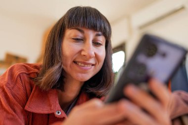 Mutlu genç kız rahat koltuğunda dinleniyor, akıllı telefondan mesaj gönderiyor, cep telefonu kullanan gülümseyen kız, evden online alışveriş yapıyor..